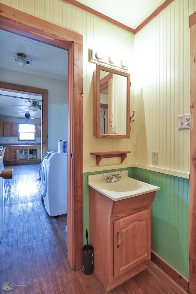 bathroom featuring wood walls, wood-type flooring, vanity, and ornamental molding