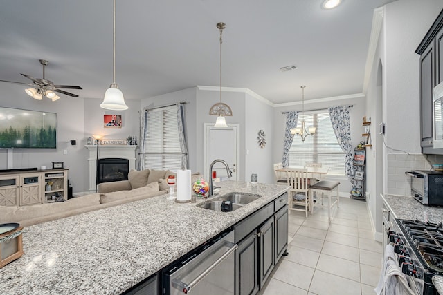 kitchen featuring light tile patterned floors, sink, decorative light fixtures, stainless steel appliances, and light stone counters