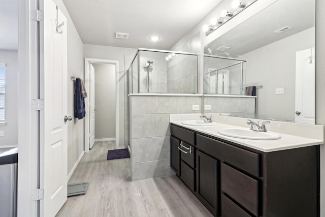 bathroom featuring vanity, hardwood / wood-style flooring, tile walls, and a shower with door