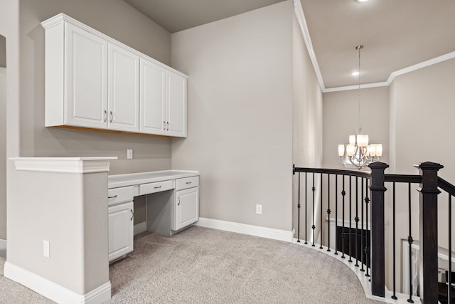 unfurnished office featuring ornamental molding, a notable chandelier, light carpet, and built in desk