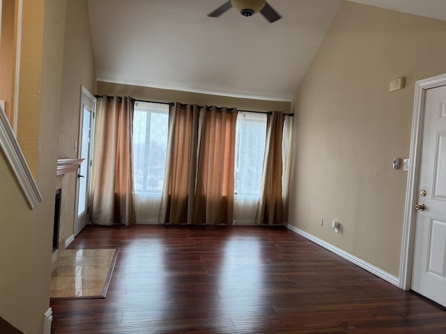 unfurnished living room featuring dark wood-type flooring, ceiling fan, a tiled fireplace, and vaulted ceiling