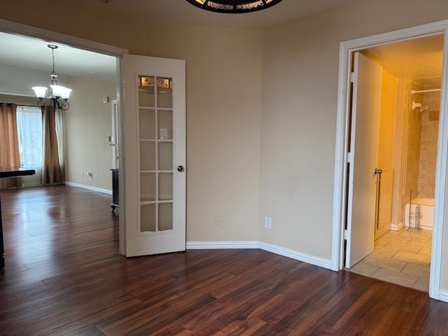 unfurnished room with a notable chandelier and dark wood-type flooring