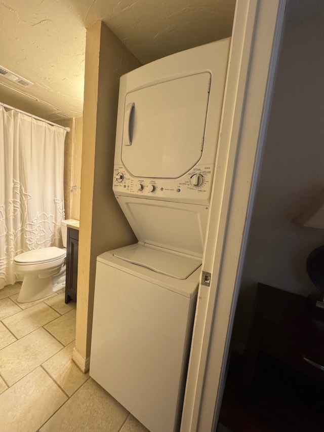 laundry area featuring stacked washer and dryer and light tile patterned floors