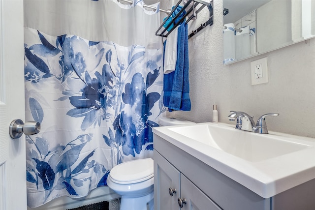 bathroom with walk in shower, vanity, and toilet