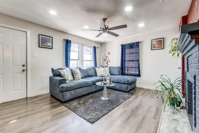 living room featuring hardwood / wood-style floors, a textured ceiling, a fireplace, and ceiling fan