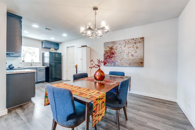 dining space with sink, a chandelier, and hardwood / wood-style floors