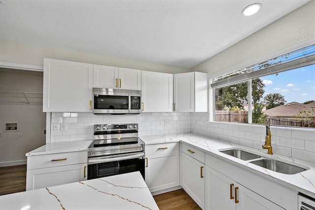 kitchen with light stone countertops, sink, white cabinetry, and stainless steel appliances