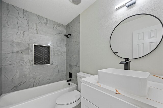 full bathroom featuring vanity, toilet, tiled shower / bath, and a textured ceiling