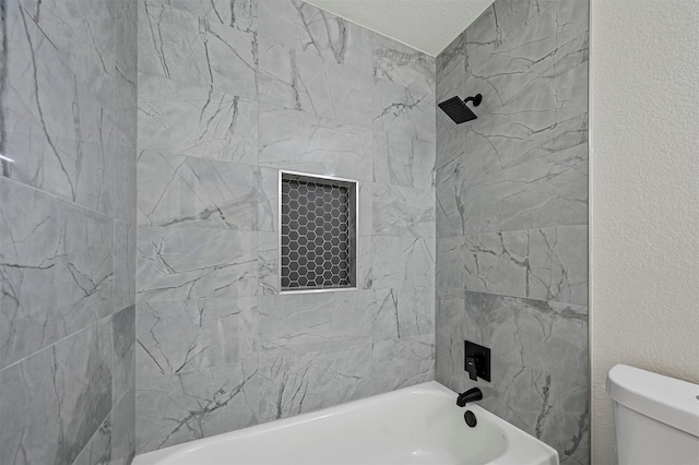 bathroom featuring tiled shower / bath combo and toilet