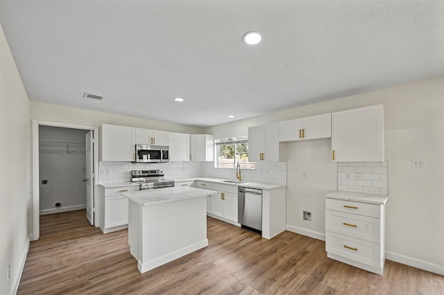 kitchen featuring a kitchen island, light hardwood / wood-style floors, white cabinetry, and stainless steel appliances