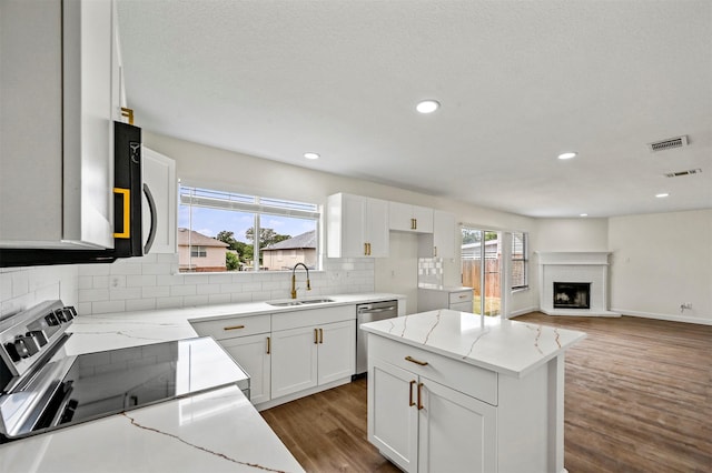 kitchen with light stone counters, sink, and white cabinets