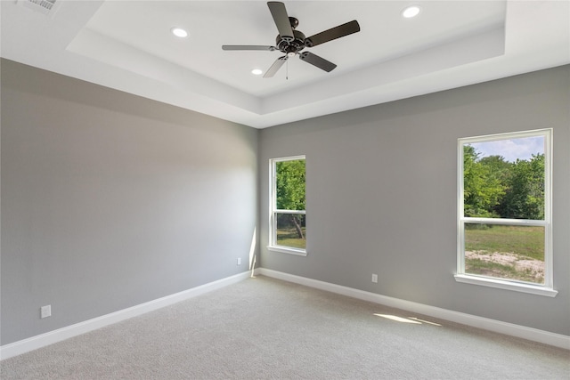 carpeted spare room featuring ceiling fan and a tray ceiling