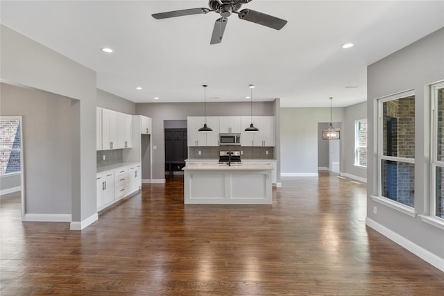 kitchen featuring hanging light fixtures, white cabinets, a center island with sink, and stainless steel appliances