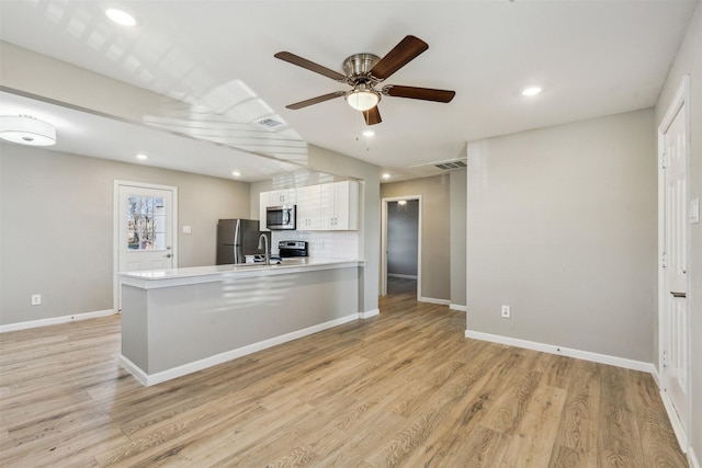 kitchen featuring white cabinetry, stainless steel appliances, decorative backsplash, kitchen peninsula, and light wood-type flooring