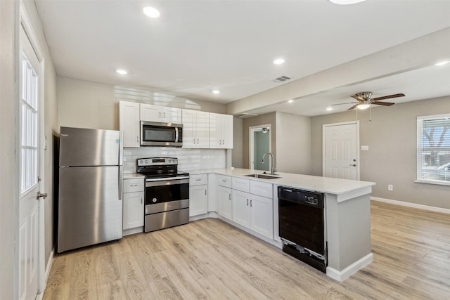 kitchen with white cabinetry, sink, kitchen peninsula, light hardwood / wood-style flooring, and stainless steel appliances