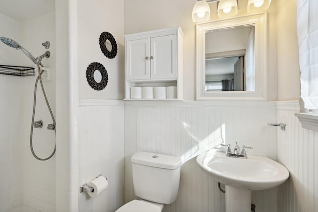 bathroom with sink, a tile shower, and toilet