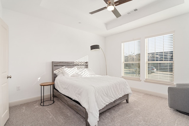 carpeted bedroom featuring ceiling fan and a raised ceiling