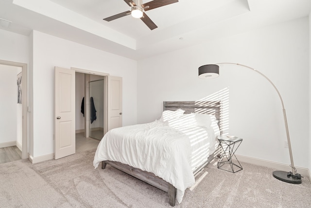 bedroom with a tray ceiling, ceiling fan, and carpet flooring