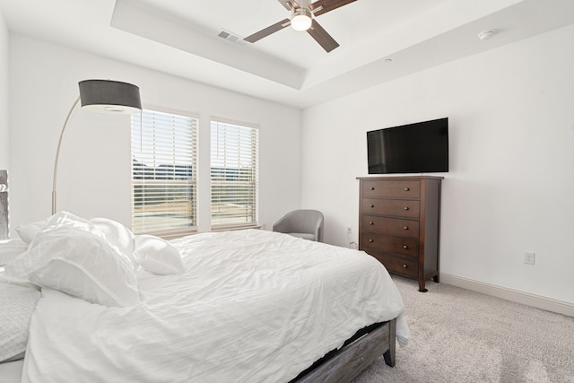 carpeted bedroom featuring a raised ceiling and ceiling fan