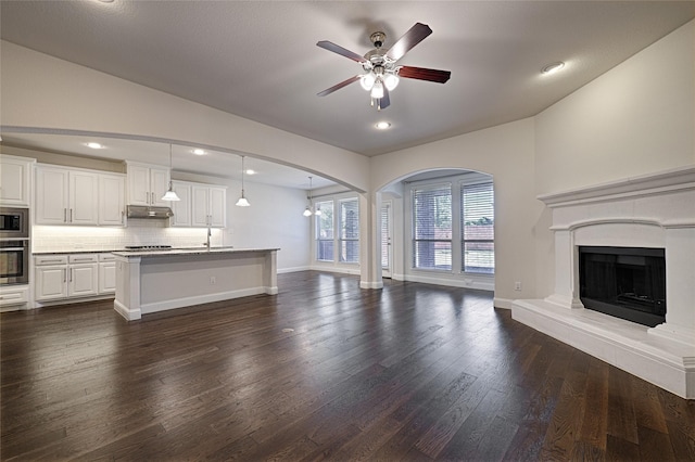 unfurnished living room with dark wood-type flooring, ceiling fan, and sink