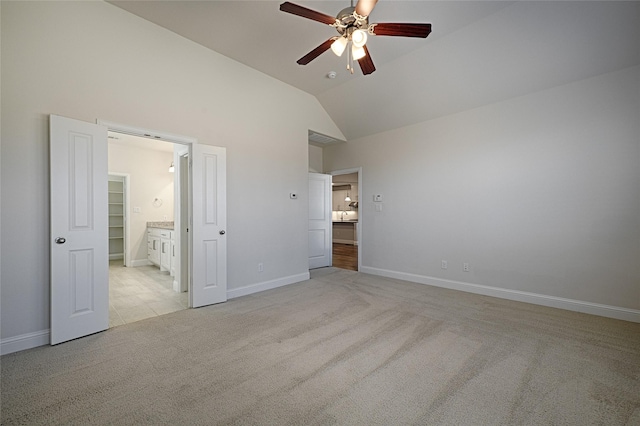 unfurnished bedroom featuring ensuite bath, vaulted ceiling, light colored carpet, and ceiling fan