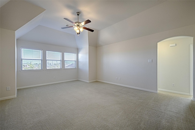 spare room with vaulted ceiling, light colored carpet, and ceiling fan