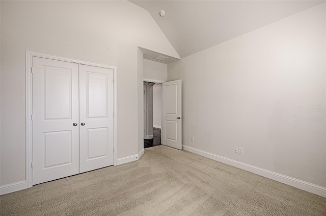 unfurnished bedroom with lofted ceiling, light carpet, and a closet