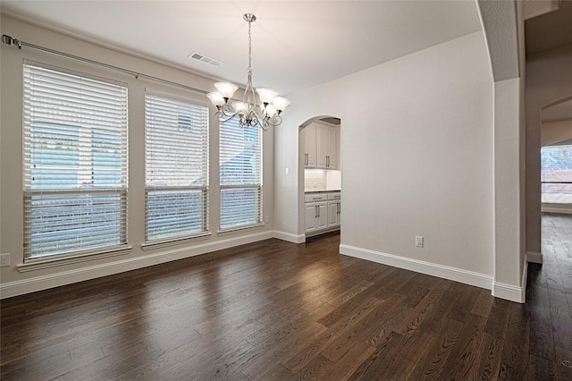 unfurnished dining area with dark hardwood / wood-style floors and a chandelier