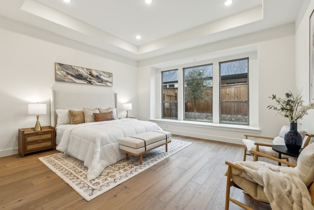 bedroom featuring light hardwood / wood-style floors and a tray ceiling