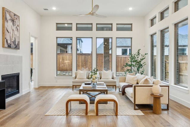 sunroom featuring ceiling fan, a tile fireplace, and a healthy amount of sunlight