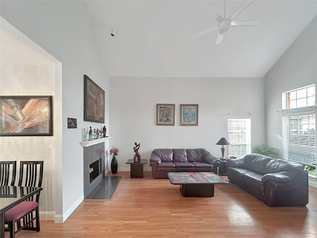 living room featuring light hardwood / wood-style flooring, high vaulted ceiling, and ceiling fan