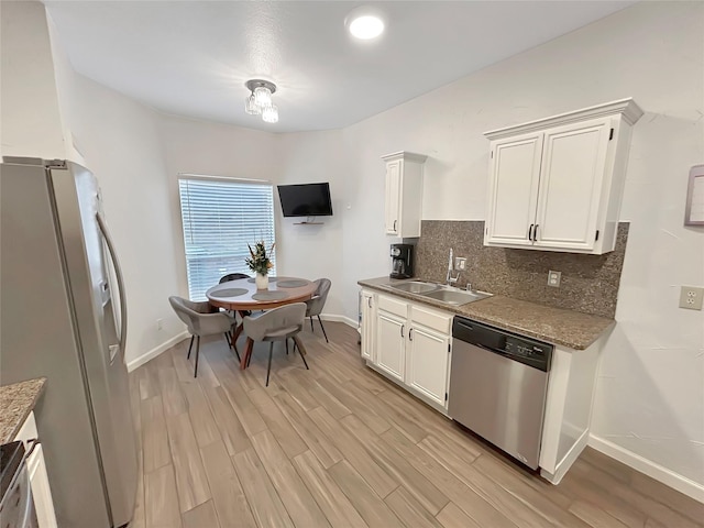 kitchen featuring sink, light wood-type flooring, stainless steel appliances, decorative backsplash, and white cabinets