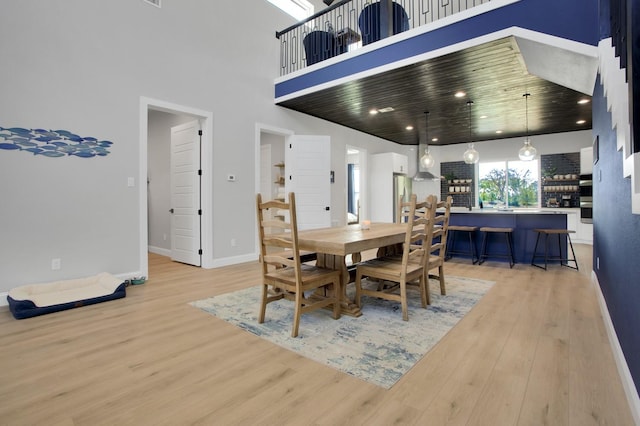 dining space featuring wood ceiling, a high ceiling, and light hardwood / wood-style floors