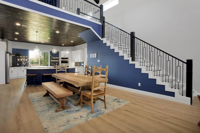 dining room with wooden ceiling, light hardwood / wood-style flooring, and a high ceiling