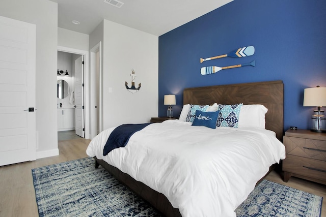 bedroom featuring connected bathroom and light wood-type flooring