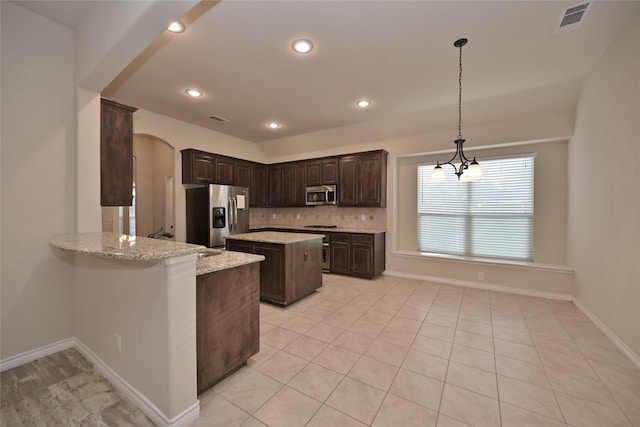 kitchen with a center island, appliances with stainless steel finishes, decorative light fixtures, kitchen peninsula, and light stone counters