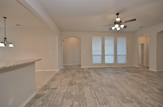 unfurnished living room featuring light hardwood / wood-style floors and ceiling fan with notable chandelier