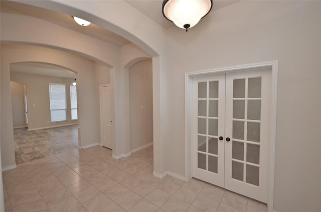 tiled empty room featuring ceiling fan and french doors