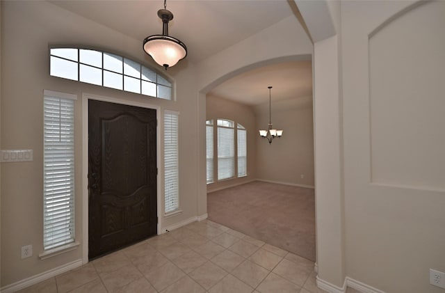 carpeted foyer entrance with an inviting chandelier