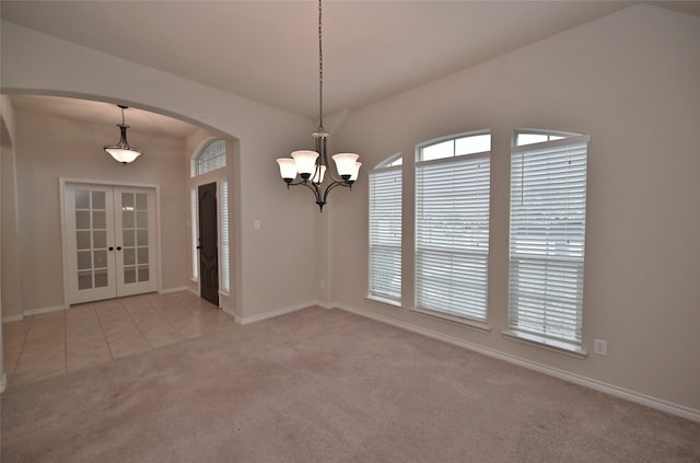 empty room with light colored carpet, a notable chandelier, and french doors