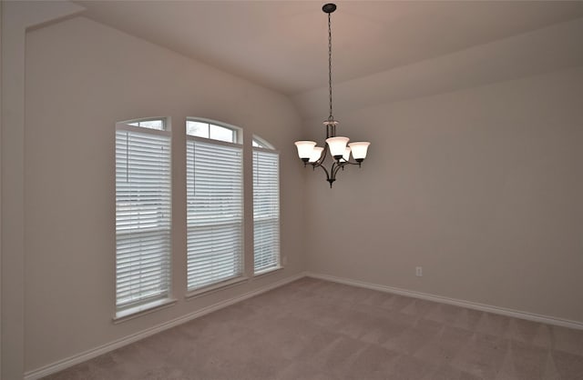 spare room with an inviting chandelier, light colored carpet, and vaulted ceiling