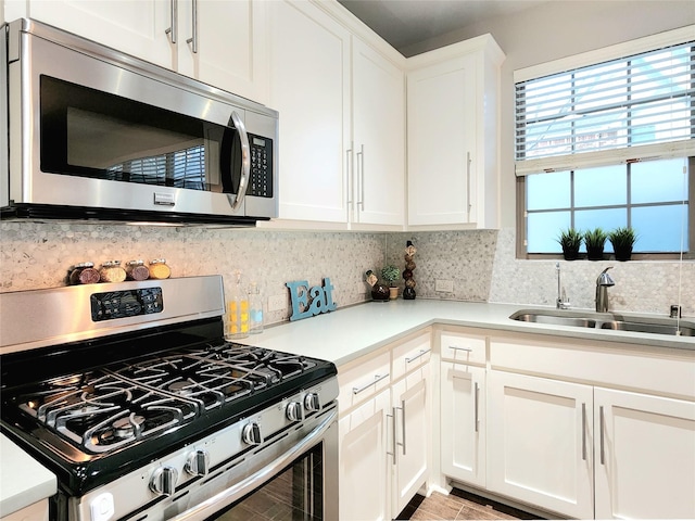 kitchen with white cabinets, appliances with stainless steel finishes, tasteful backsplash, and sink