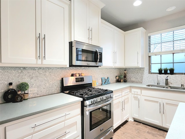 kitchen with sink, white cabinets, tasteful backsplash, and appliances with stainless steel finishes