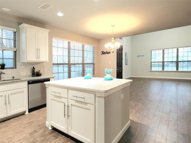 kitchen with white cabinets, a center island, decorative light fixtures, sink, and stainless steel dishwasher