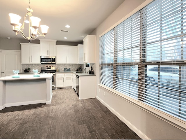 kitchen featuring wood-type flooring, white cabinets, sink, decorative light fixtures, and stainless steel appliances