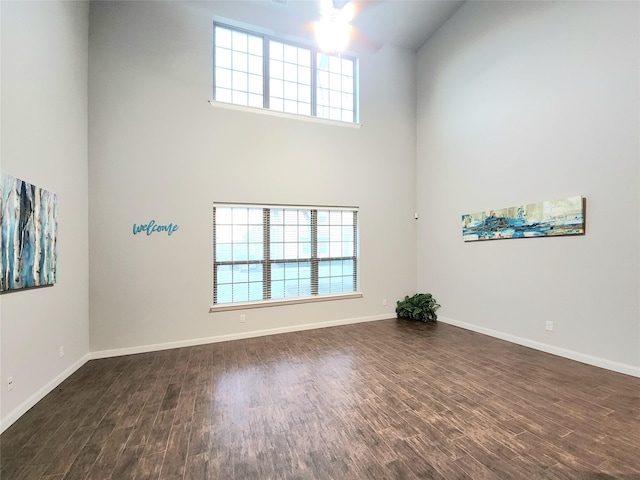 empty room with a towering ceiling and dark hardwood / wood-style flooring