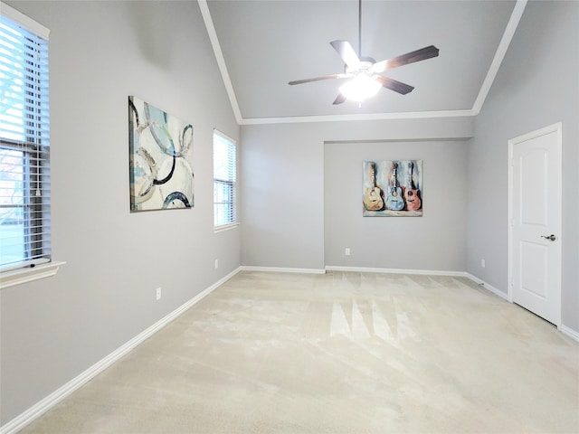 empty room with ornamental molding, vaulted ceiling, ceiling fan, and light colored carpet