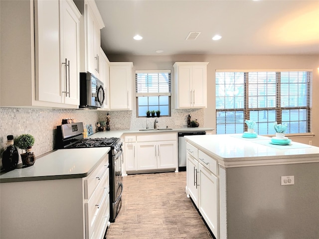 kitchen with tasteful backsplash, sink, a kitchen island, white cabinets, and stainless steel appliances