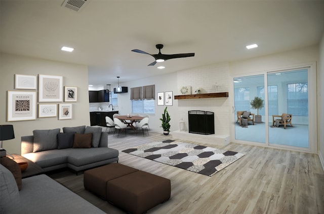 living room featuring ceiling fan, light hardwood / wood-style flooring, a wealth of natural light, and a brick fireplace