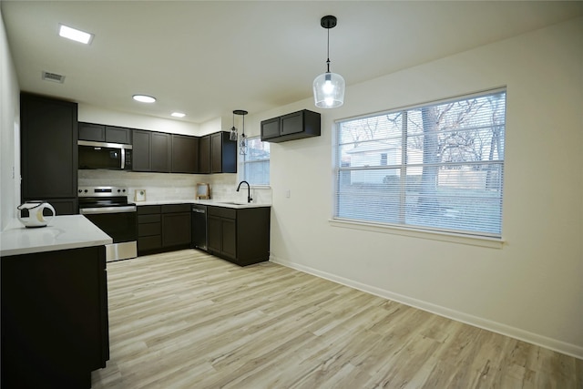 kitchen with pendant lighting, sink, backsplash, light hardwood / wood-style floors, and stainless steel appliances